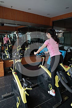 Asian chinese Fitness young woman on gym bike spinning