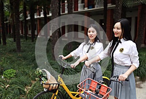 Relax Asian Chinese pretty girls wear student suit in school enjoy free time ride bike in nature spring garden