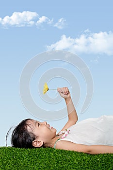 Asian Chinese girl lying on the grass and holding flower