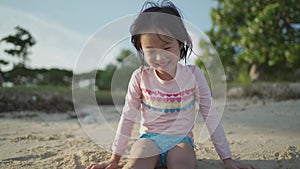 Asian chinese girl playing with sand, hiding her legs in sand