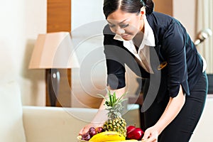 Asian Chinese hotel housekeeper placing fruit