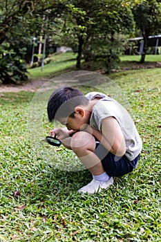 Asian Chinese little boy looking through magnifying glass