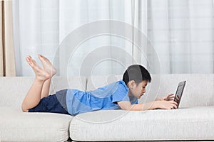 Asian Chinese little boy using laptop on the sofa
