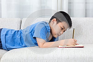 Asian Chinese little boy writing book on the sofa