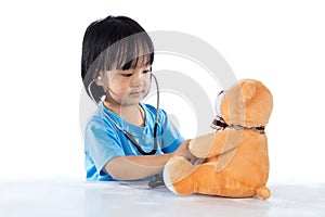 Asian Chinese little doctor girl examine teddy bear