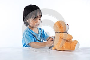 Asian Chinese little doctor girl examine teddy bear