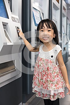 Asian Chinese little girl buying admission ticket at MRT station