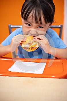 Asian Chinese little girl eating burger