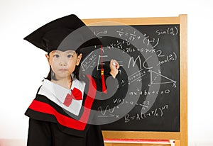 Asian Chinese little girl in graduation gown againts blackboard