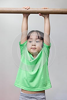 Asian Chinese little girl hanging on horizontal bar