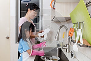 Asian Chinese little girl helping mother washing dishes