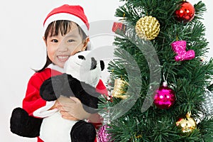 Asian Chinese little girl holding panda doll posing with Christmas Tree