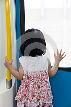 Asian Chinese little girl inside train looking beside the window