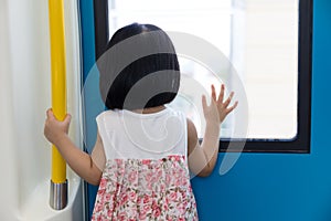 Asian Chinese little girl inside train looking beside the window