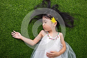 Asian Chinese little girl lying on the grass with flower