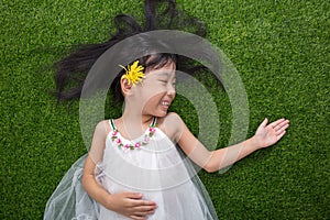 Asian Chinese little girl lying on the grass with flower