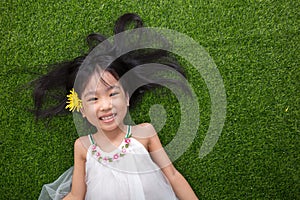 Asian Chinese little girl lying on the grass with flower