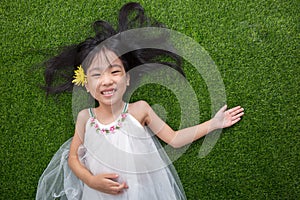 Asian Chinese little girl lying on the grass with flower