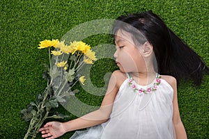 Asian Chinese little girl lying on the grass with flowers