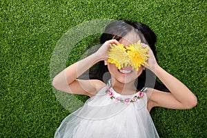 Asian Chinese little girl lying on the grass with flowers