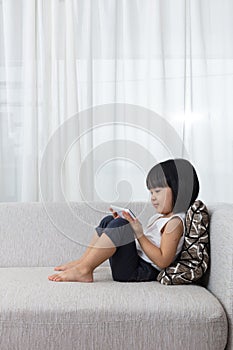 Asian Chinese little girl lying on the sofa with phone