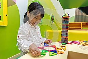 Asian Chinese little girl playing colorful magnet plastic blocks