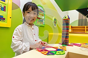 Asian Chinese little girl playing colorful magnet plastic blocks