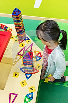 Asian Chinese little girl playing colorful magnet plastic blocks