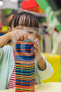 Asian Chinese little girl playing colorful magnet plastic blocks