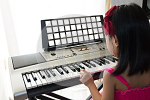 Asian Chinese little girl playing electric piano keyboard