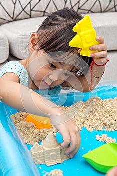 Asian Chinese little girl playing kinetic sand at home