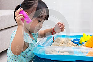 Asian Chinese little girl playing kinetic sand at home