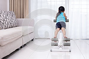 Asian Chinese little Girl playing workout machine in the living