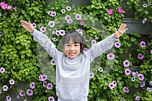 Asian chinese little girl posing next to Morning Glory flowers w