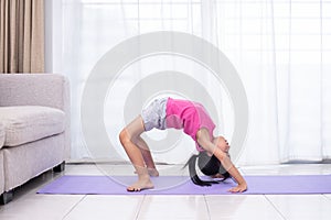 Asian Chinese little girl practicing yoga pose on a mat