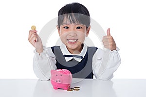 Asian Chinese little girl putting coins into piggy bank