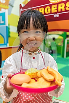 Asian Chinese little girl role-playing at burger store