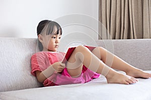 Asian Chinese little girl sitting on the sofa reading book