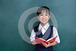 Asian Chinese little Girl in uniform reading book against green