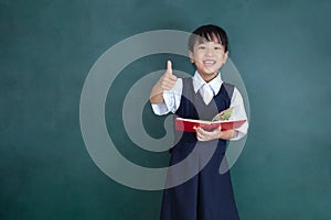 Asian Chinese little Girl in uniform showing thumbs up against g