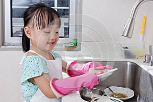 Asian Chinese little girl washing dishes in the kitchen photo