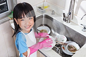 Asian Chinese little girl washing dishes in the kitchen