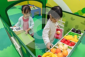 Asian Chinese little girls role-playing at fruits store