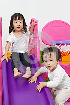 Asian Chinese little sister and brother playing on the slide