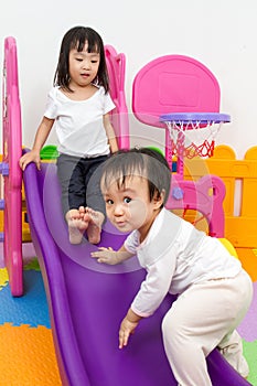 Asian Chinese little sister and brother playing on the slide