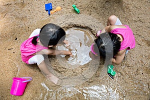 Asian Chinese little sister playing sand at creek