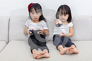 Asian Chinese little sisters playing TV games on the sofa