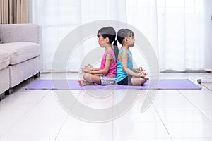 Asian Chinese little sisters practicing yoga pose on a mat