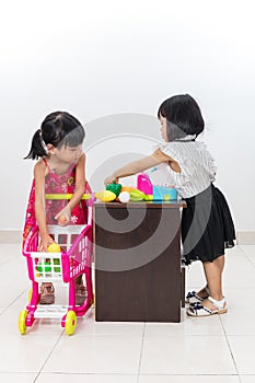 Asian Chinese little sisters pretending customer and cashier wit
