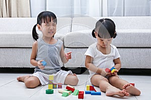 Asian Chinese little sisters struggle for blocks photo